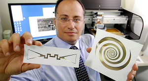 Манос Тенцерис демонстрирует напечатанные на бумаге сенсор и ультраширокополосную антенну, применяемые для сбора электромагнитной энергии